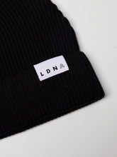 Load image into Gallery viewer, Close up of LDNA logo on the LDNA London black fisherman style beanie.
