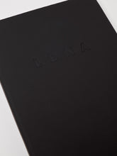 Load image into Gallery viewer, LDNA London black notebook close up showing embossed effect of the LDNA logo.
